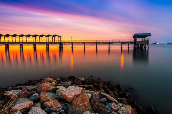 Puesta de sol en el mar. Muelle y playa