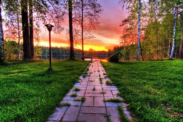 Pôr do sol no lago no parque. Trilha e lanterna