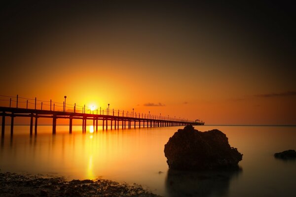 Paisaje de un puente largo al atardecer sobre la superficie del agua