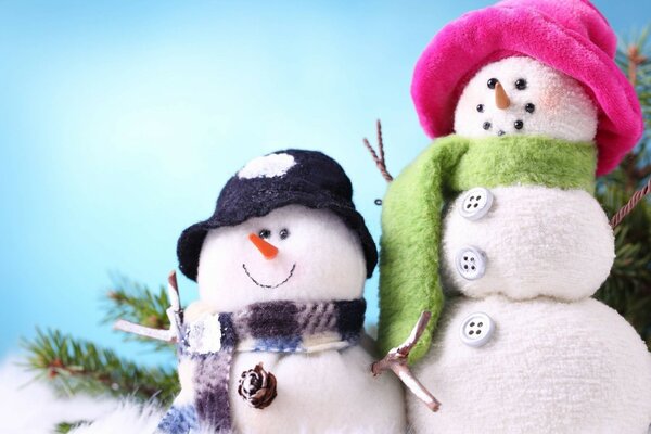 2 bonhommes de neige à côté d une branche de sapin