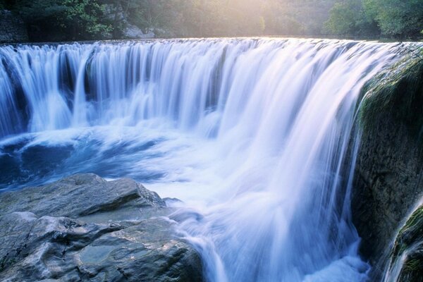 Stürmischer Wasserfall unter Steinen