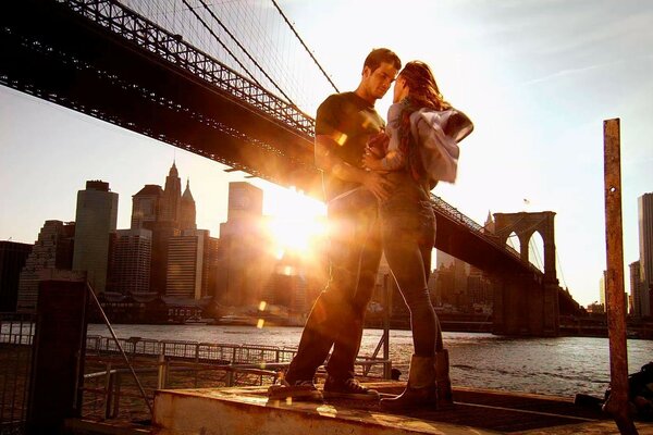 A girl and a guy by the river under the bridge