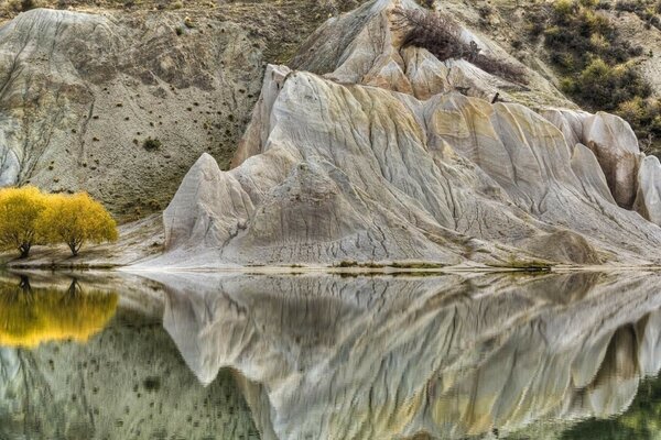 Los árboles amarillos de las montañas de fondo se reflejan en el agua