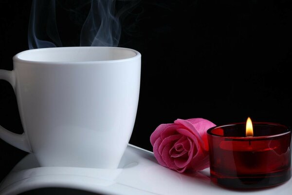 Tasse, rose et bougie sur fond noir