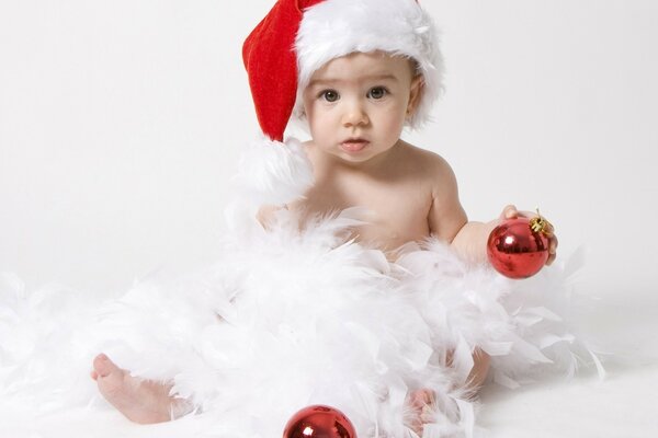 A child in a New Year s hat, in feathers and with a New Year s ball