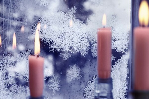 Lit pink candles on a background of frozen glass