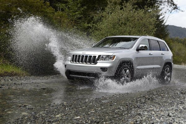 A silver SUV cuts through the river