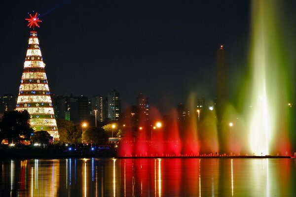 City Christmas tree and glowing fountain on the river