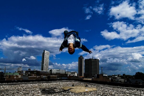 A guy doing parkour performs a backflip on the roof