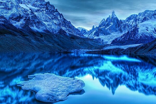 An icy blue lake among snow-capped mountains