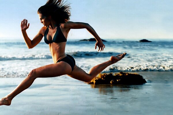 La ragazza corre lungo la costa del mare