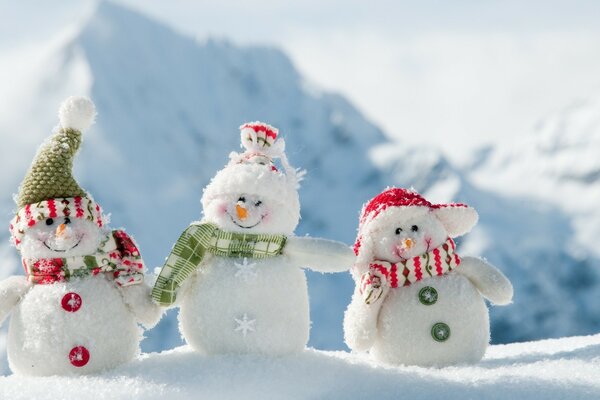 Tres muñecos de nieve en el fondo de las montañas