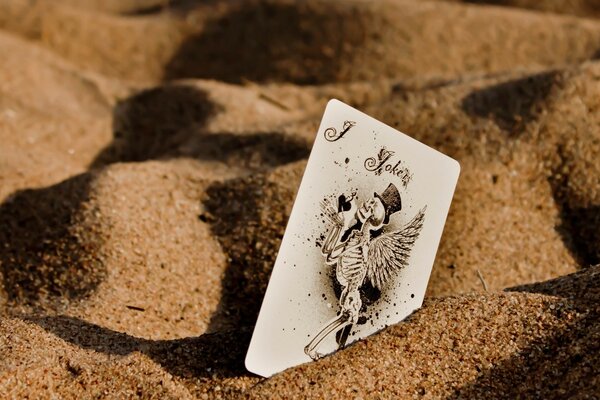 The joker card on the sand in the desert