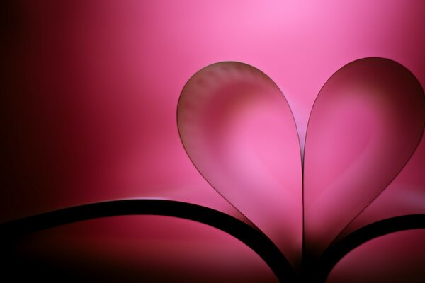 A heart from the pages of a book on a pink background