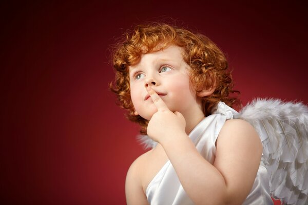 Un bambino con i capelli rossi ricci a immagine di un angelo