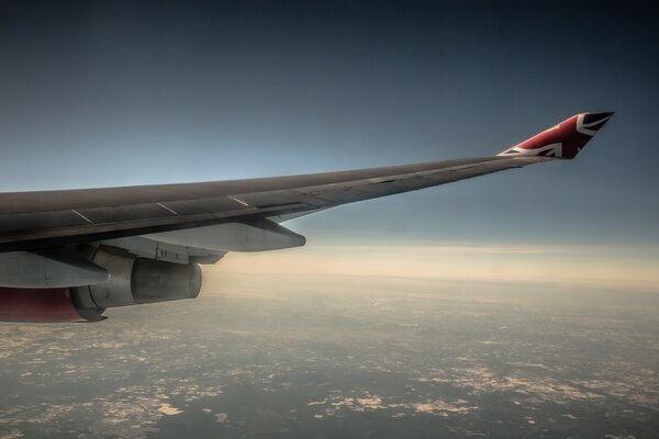 The wing of a flying plane over the city