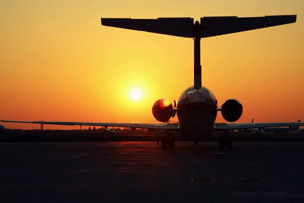 The tail of the plane against the orange evening sky