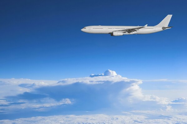 A white plane is flying above the clouds