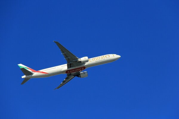 A snow-white airliner in a bright blue sky