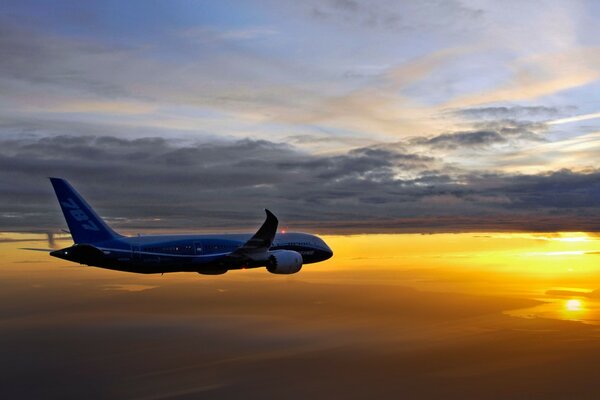 The plane flies at dawn above the clouds