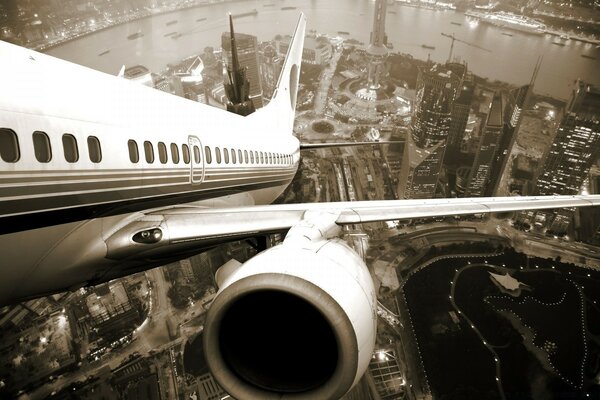 The plane flies over the city in lights