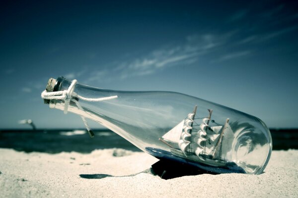 Schiff in einer Flasche aus dem Meer im Sand