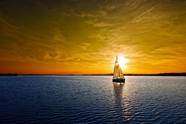 Un velero camina sobre la superficie del agua al atardecer