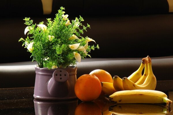 Bananas and oranges on the table with flowers