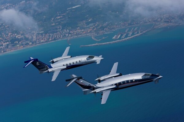 Two private planes fly along the coast