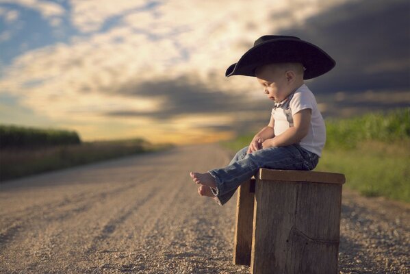 A young cowboy gathers strength sitting on a homemade stool