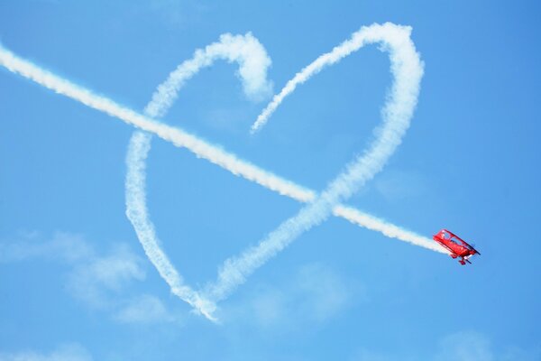 Avión rojo dibujando un corazón en el cielo