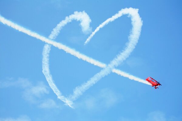 Avion rouge dessinant un coeur dans le ciel