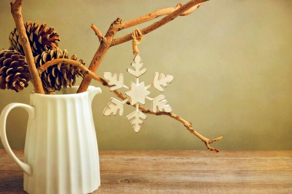 Still life with twigs in a jug, fir cones and a snowflake