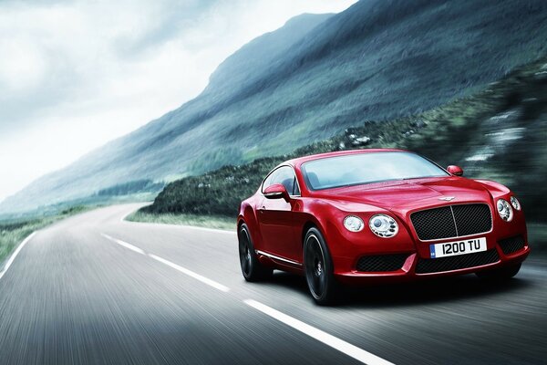 Foto del coche deportivo Bentley en el fondo de la carretera y las montañas