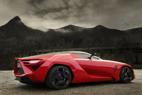 Hermoso coche rojo se encuentra frente a las montañas