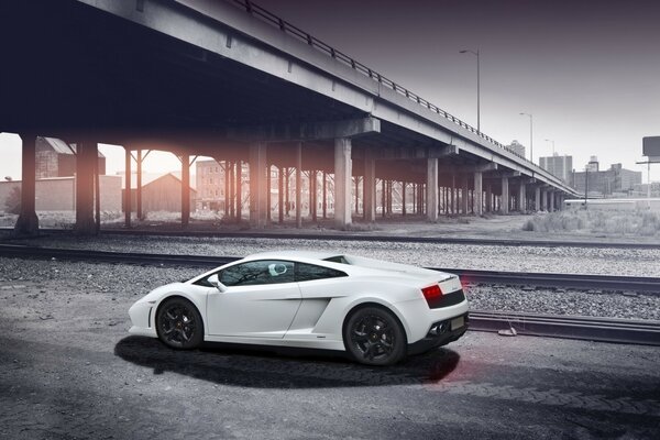 A white foreign car on the background of a rail road