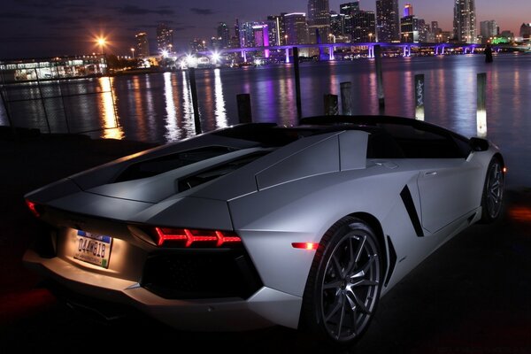 White car on the background of reflections of the city in the river