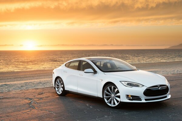 White car on the beach at sunset