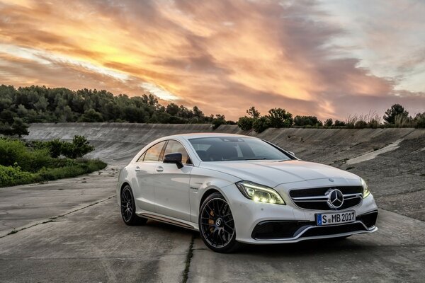 Coche con faros luminosos en el fondo de la puesta de sol