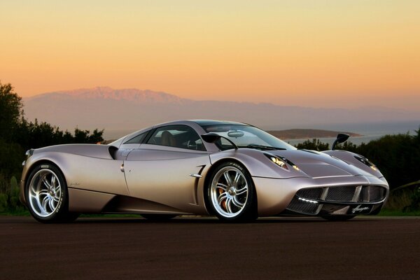 Coche de carreras plateado en el fondo de la puesta de sol