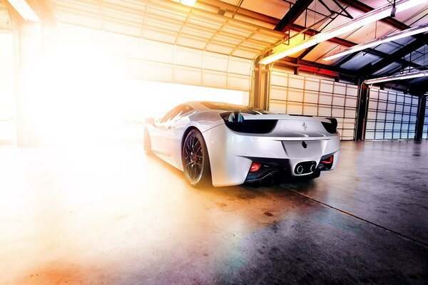 Ferrari blanche à la sortie du garage à la lumière du soleil