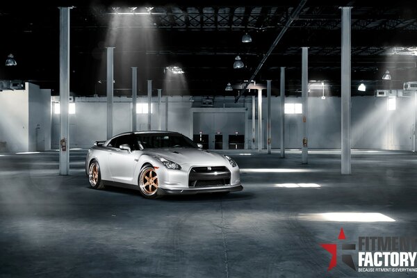 Voiture de sport grise dans un hangar vide