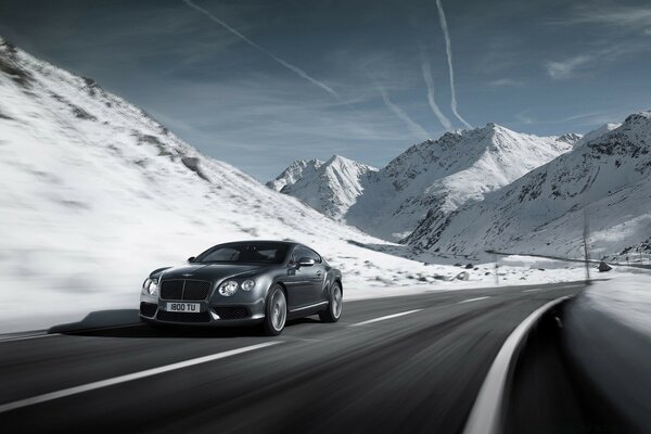 Moving black car in snowy mountains