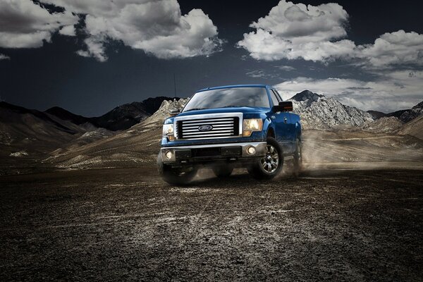 A blue jeep moving on pebbles in the mountains