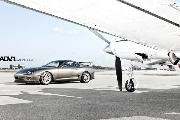 A sports car is parked near the plane