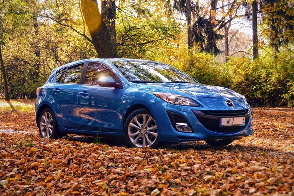 New blue Mazda car in the autumn forest