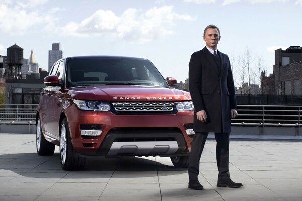 James Bond is standing next to the car