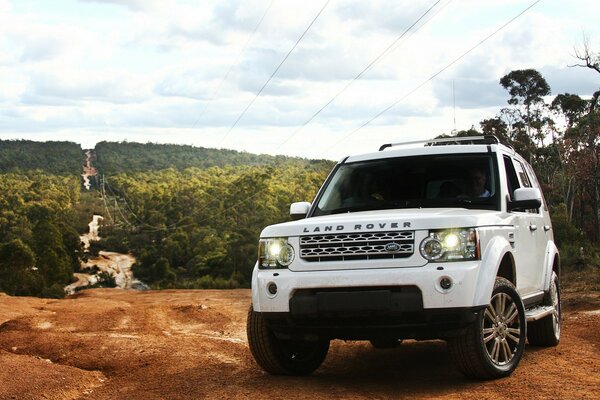 Um Land Rover branco na estrada. Paisagem com floresta