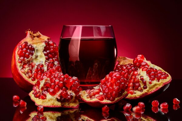 Melograno con bicchiere di vino su sfondo rosso