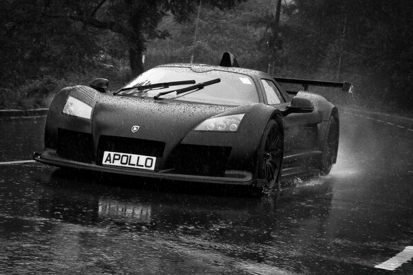 A black car rushes down the road in the rain